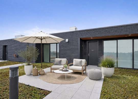 A modern patio with a table and chairs and a large umbrella.