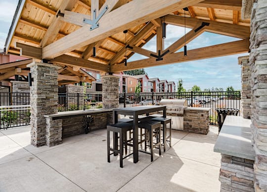 A patio with a table and chairs under a wooden roof.