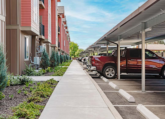 A red car is parked in a parking lot next to a building.