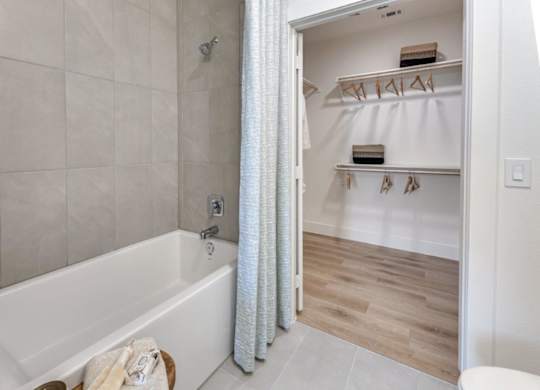 A white bathroom with a tub and a walk in closet.
