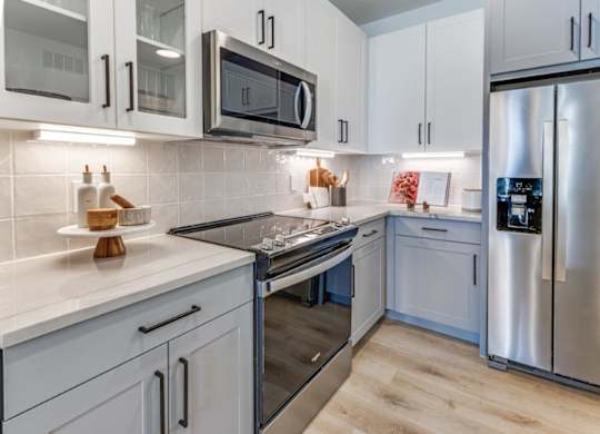 A modern kitchen with a stainless steel refrigerator, microwave, and oven.