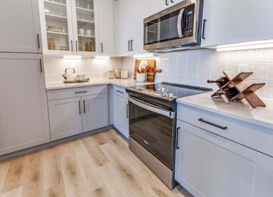 A kitchen with a wooden floor and a stainless steel oven.