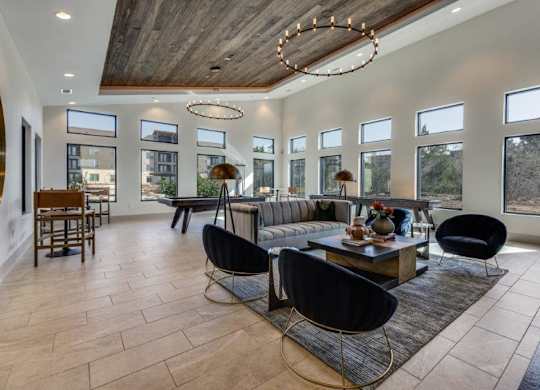 A modern living room with a large wooden table and black chairs.