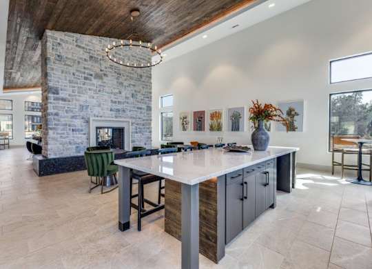 A modern kitchen with a stone fireplace and a large island.