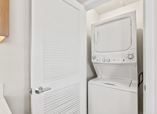 a white washer and dryer in a closet next to a white door