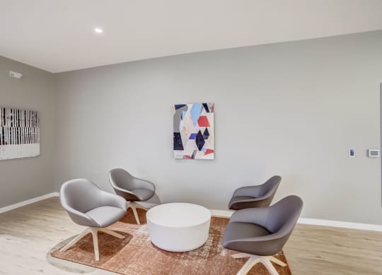a living room with chairs and a table and artwork on the wall