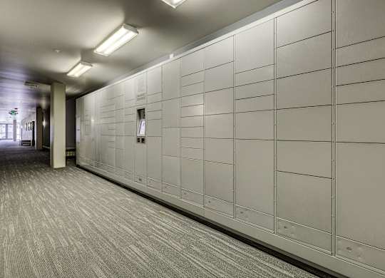 A long hallway with a white wall and grey carpet.