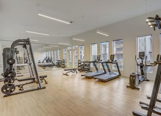 a gym with treadmills and other exercise equipment and windows