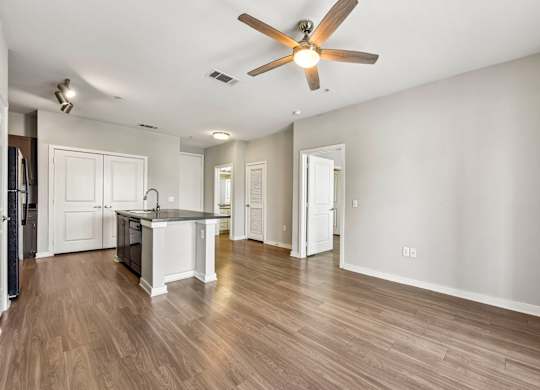 A spacious room with a ceiling fan and wooden flooring.