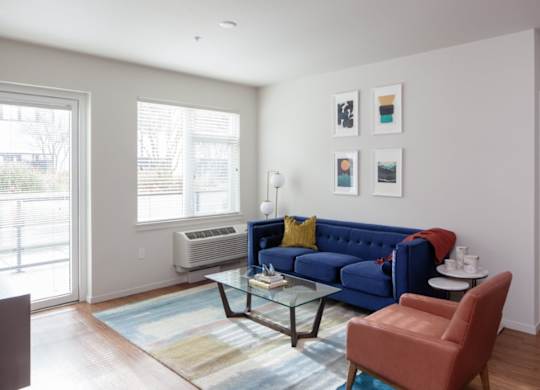 A living room with a blue couch, a red chair, and a glass coffee table.