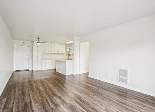 A large empty room with wooden floors and white walls.