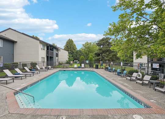 A swimming pool surrounded by lounge chairs and trees.