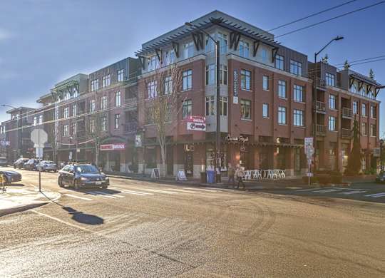A street view of a multi-story building with cars parked in front.