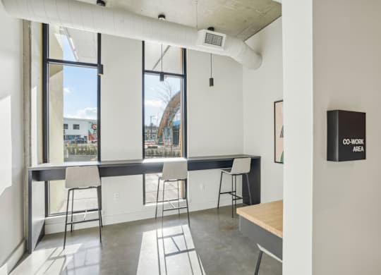 A room with a long table and chairs with a sign on the wall that says "CO-WORK AREA".