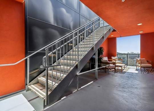 A staircase with a metal railing and steps leading up to a balcony.
