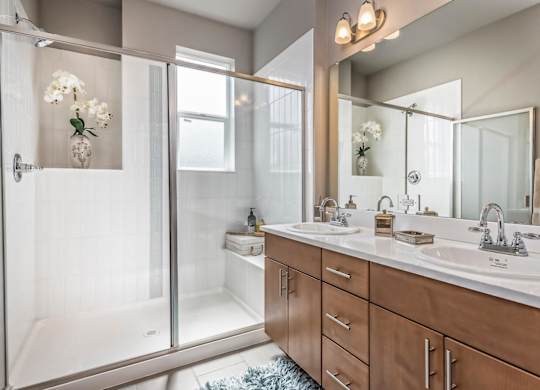 A bathroom with a walk-in shower and double sinks.