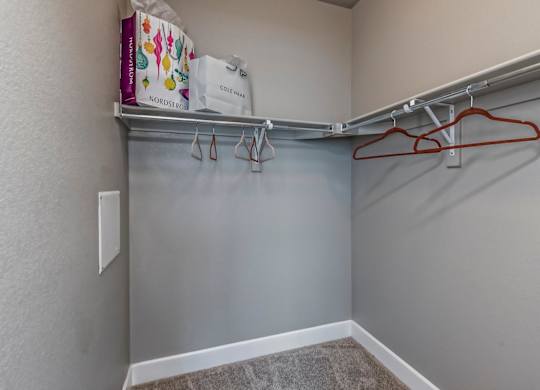 A closet with a grey wall and a red hanger.