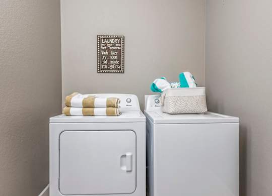 Two white washing machines with towels on top.