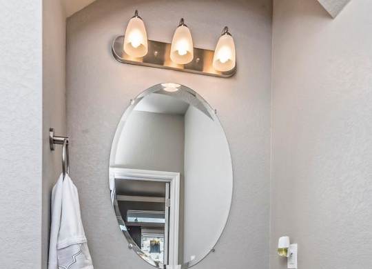 A white sink with a round mirror above it.