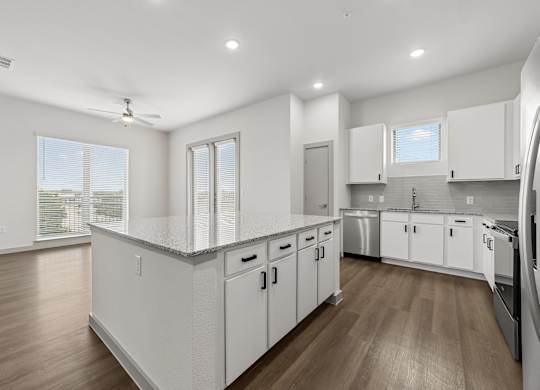 A modern kitchen with white cabinets and wooden floors.