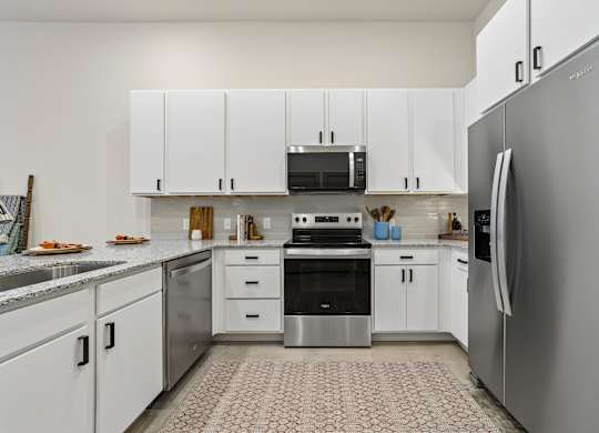 A modern kitchen with white cabinets and stainless steel appliances.