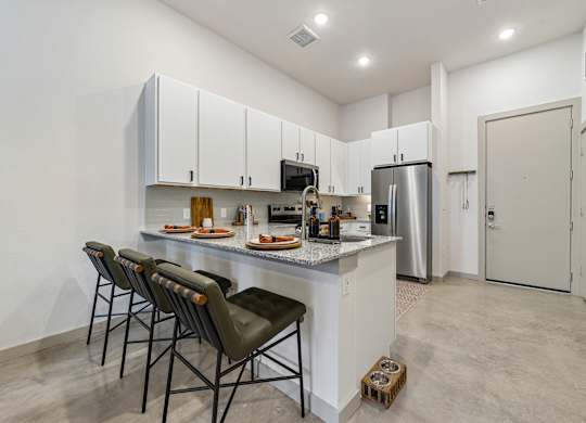 A kitchen with white cabinets and a white countertop with a refrigerator and a sink.