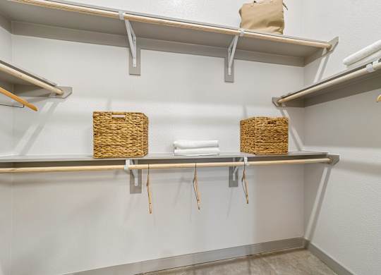 A white wall with three shelves and two baskets on them.