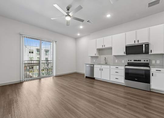 A kitchen with white cabinets and a wooden floor.