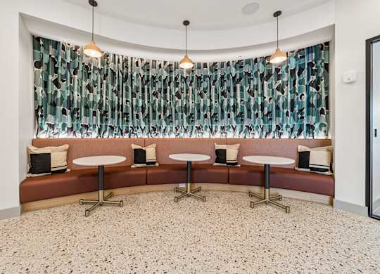 A room with a bench and a table with a curtain in the background.