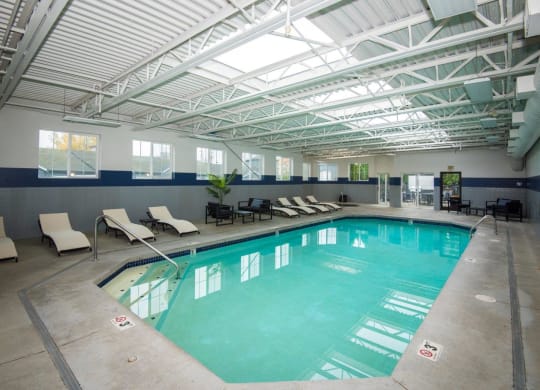a large indoor swimming pool with chaise lounge chairs and a ceiling with skylights