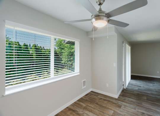 A room with a ceiling fan and a window with blinds.