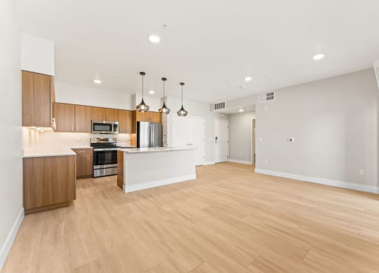 an open kitchen and living room with wood floors and white walls