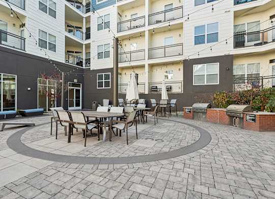 A patio with a table and chairs is surrounded by apartment buildings.