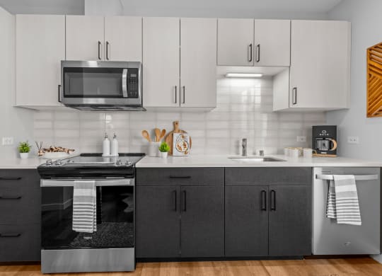 Gridline Apartments Kitchen with Stainless Steel Appliances and White Upper Cabinets and Gray Lower Cabinets