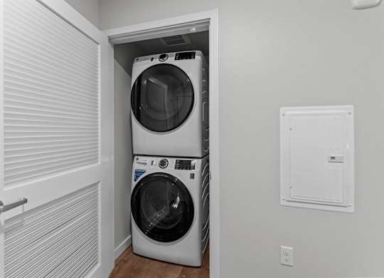 A white washer and dryer are stacked in a small laundry room.