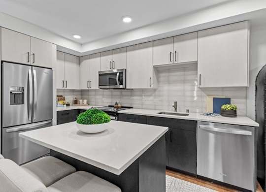 A modern kitchen with a white countertop and stainless steel appliances.