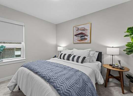 A bedroom with a large bed and a small table with a lamp on it.