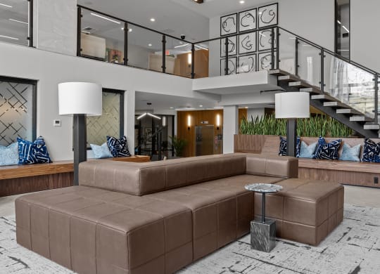 a living room with a brown couch and a staircase