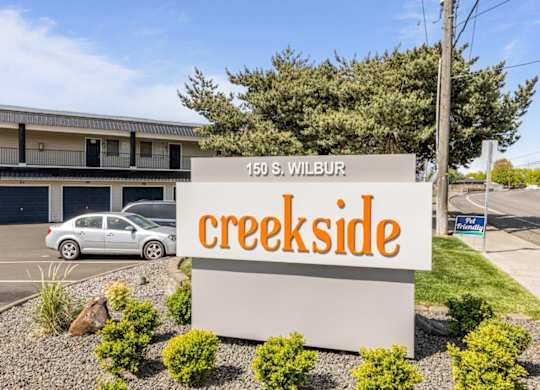 A sign for Creekside apartment complex stands in front of a building.