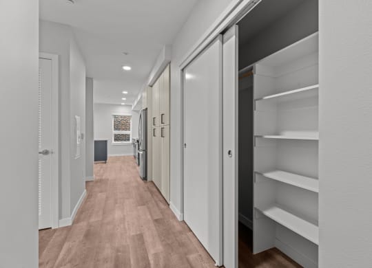 a long hallway with white closets and wood floors