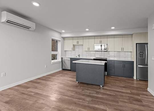 A kitchen with a refrigerator, sink, and cabinets.