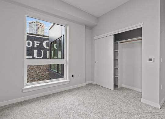 A room with a large window and a door leading to another room.