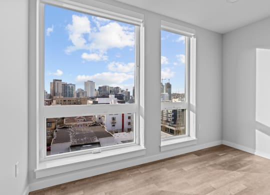 a living room with three windows and a view of the city
