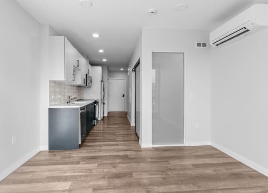 a renovated apartment with white walls and wood flooring and a kitchen