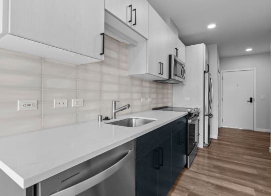 a kitchen with white countertops and a stainless steel sink