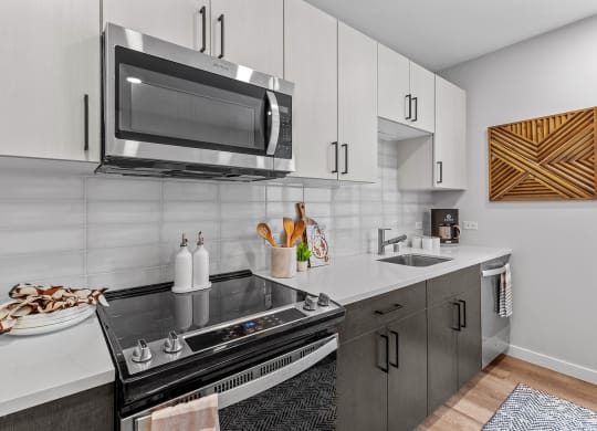 Gridline Apartments Kitchen with Stainless Steel Appliances and White Cabinets