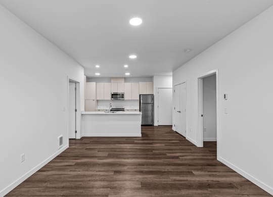 the living room and kitchen of a new home with white walls and wood floors
