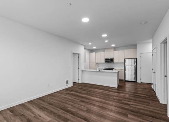 the living room and kitchen in a new home with white walls and wood flooring