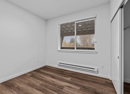 the living room of an apartment with wood flooring and a window