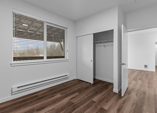 an empty bedroom with a large window and a closet